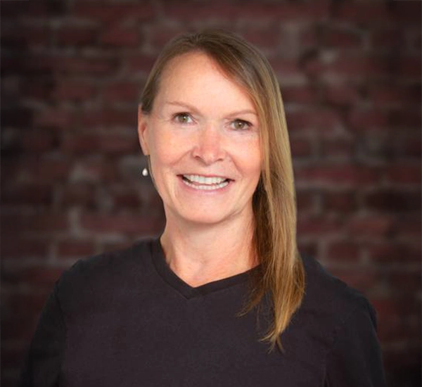 Cheri Stewart smiling in front of a brick wall.